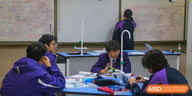 Two male students in school uniform focus intently while working together on a practical science experiment in the chemistry lab at Living Word Shanghai.