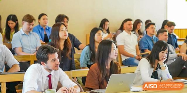 A diverse group of high school students attentively listening to a lecture or presentation in a bright and engaging classroom setting at Living Word Shanghai.