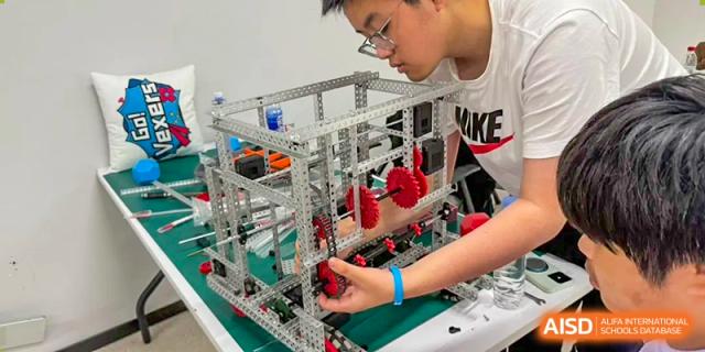A student carefully manipulates the components of an advanced metal robotics build, demonstrating precision skills at Living Word Shanghai.