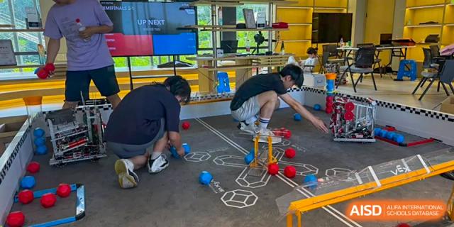 Students test their remote-controlled robot on a marked competition mat, practicing for a robotics challenge at Living Word Shanghai.