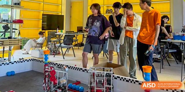 A team of students stands together, preparing their robot for testing in a dedicated STEM laboratory at Living Word Shanghai.