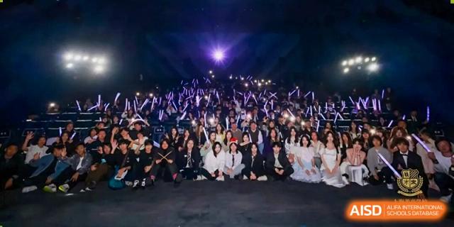 A large group photo of students and staff dressed in formal attire, gathered on tiered seating for a major evening school event, Living Word Shanghai.