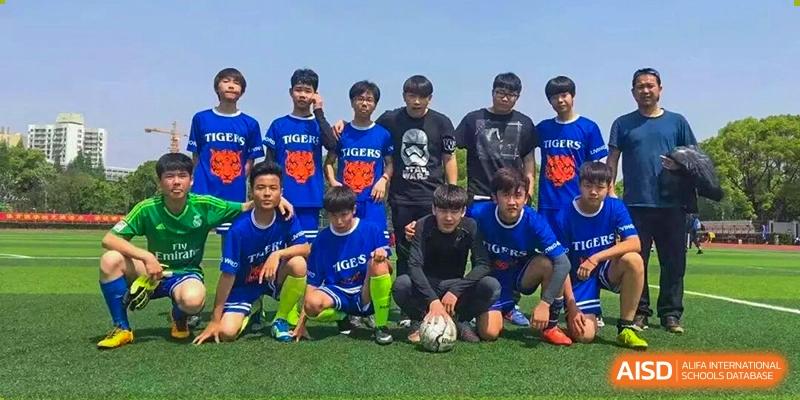 A school soccer team wearing bright blue and yellow uniforms posing for a group picture on a grassy field with soccer balls, Living Word Shanghai.