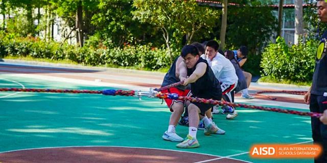 A close-up shot of students passionately battling in a tug-of-war match on the green field during a friendly sports competition at Living Word Shanghai.