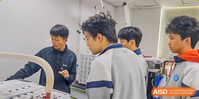 A close-up of several male students in school uniforms collaborating and examining equipment or materials in a focused, hands-on lab environment at Jian Ping High School.
