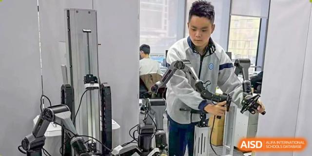 A male student operates or calibrates a robotic arm and complex machinery in a technical or engineering workshop at Jian Ping High School.