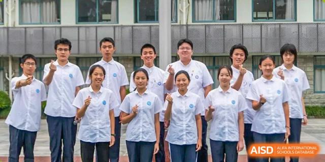 A group of seven students, both male and female, stand side-by-side in matching white school uniforms, smiling at the camera at Jian Ping High School.