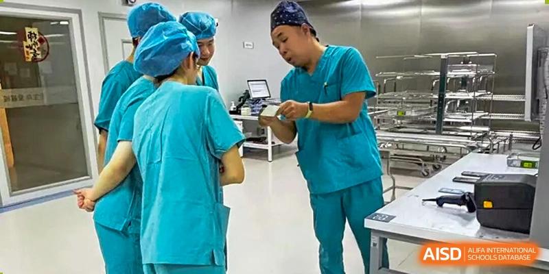 Two individuals in surgical scrubs and caps examine a device or document in a clinical setting, Jian Ping High School.
