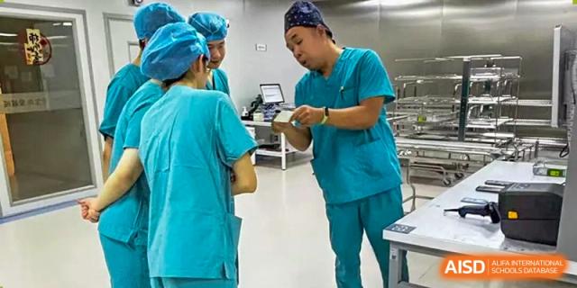 Two individuals in surgical scrubs and caps examine a device or document in a clinical setting, Jian Ping High School.