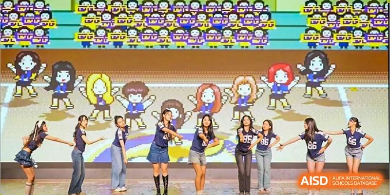 Five female students performing a synchronized dance routine on a stage with a brightly colored, animated backdrop, Jian Ping High School.
