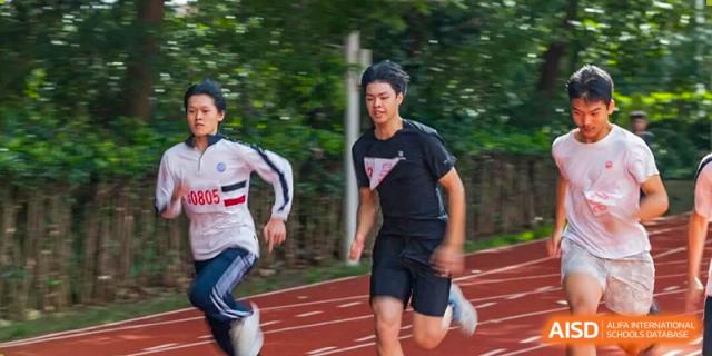 Two young men intensely competing in a track and field sprint event, captured with a blurred background suggesting high speed on the running track, Jian Ping High School.