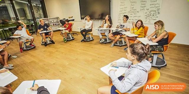 Older students are seated in a dynamic, circular arrangement in a bright classroom, actively participating in a lesson or discussion at The British International School Shanghai, Puxi.