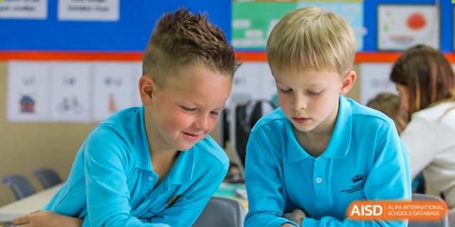 Two young boys with light hair are deeply engaged in a shared activity or looking at a learning resource together at The British International School Shanghai, Puxi.