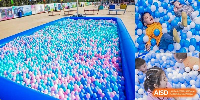 A massive inflatable pool filled with thousands of pink and blue plastic balls, creating a fun and colorful ball pit for children to play in at The British International School Shanghai, Puxi.