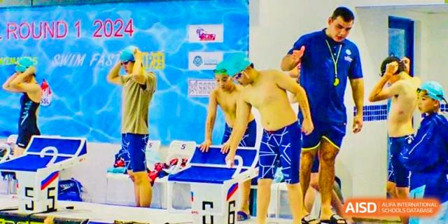 Two male swimmers are climbing out of the pool onto the platform after finishing a race during a competition at The British International School Shanghai, Puxi.