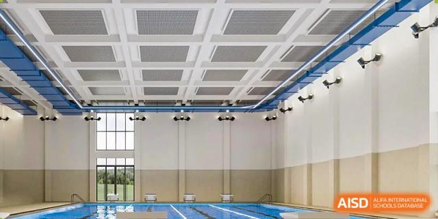 An empty, modern indoor swimming pool facility with marked blue lanes is shown, suitable for swimming competitions at The British International School Shanghai, Puxi.