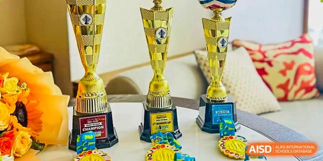 A display of several tall, golden championship trophies and smaller medals symbolizes sporting success at The British International School Shanghai, Puxi.