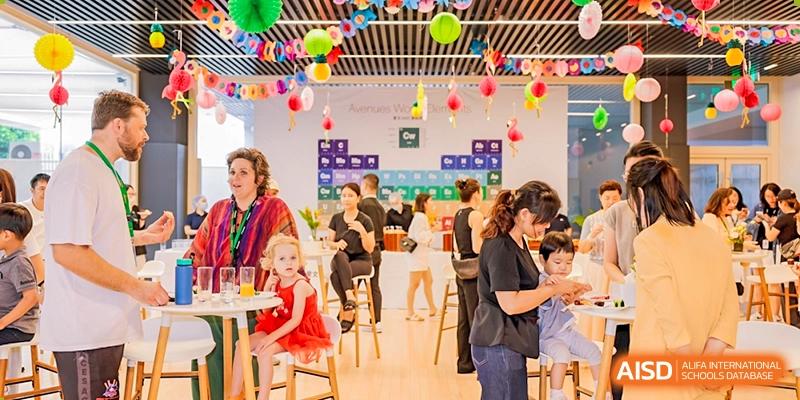 A casual gathering or party indoors with adults and children seated at tables decorated with balloons, Avenues: The World School.