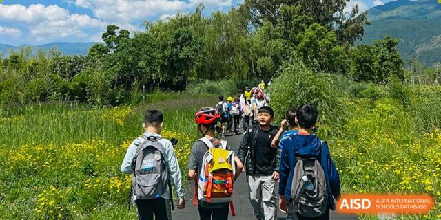 A group of students wearing backpacks walk uphill on a path during an outdoor hiking or field trip adventure, Avenues: The World School.
