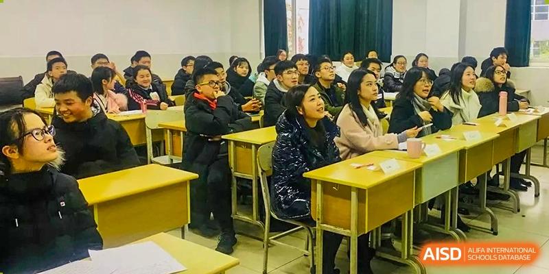 Students sit at desks in a tiered lecture hall, listening attentively to a presentation at International Studies Center Of Chongqing Nankai Secondary School.
