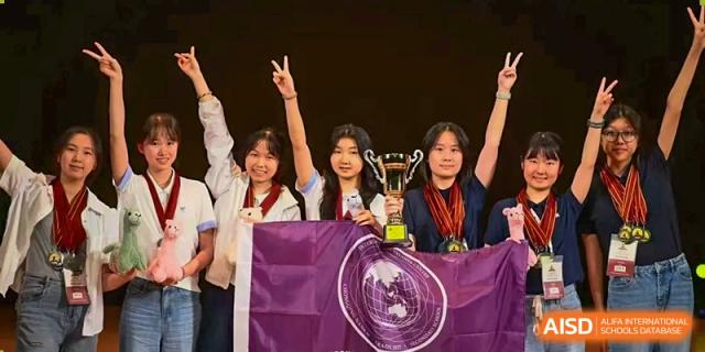 Three female students smile and hold a trophy along with a large purple flag at International Studies Center Of Chongqing Nankai Secondary School.