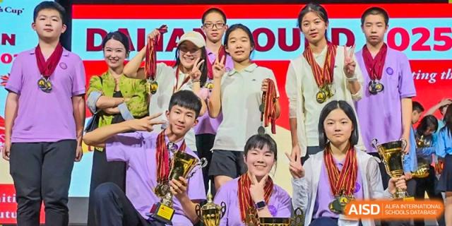 A group of students celebrate their victory by holding trophies and medals on a red stage at International Studies Center Of Chongqing Nankai Secondary School.