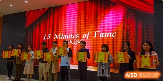 Students stand on a stage lit with red lights during a "15 Minutes of Fame" performance at International Studies Center Of Chongqing Nankai Secondary School.