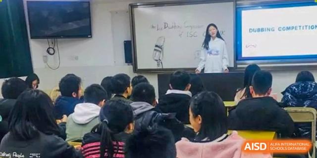 A student stands at the front of a classroom presenting her work to classmates at International Studies Center Of Chongqing Nankai Secondary School.