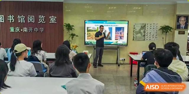An educator stands at the front of a classroom using a digital screen to teach a lesson at International Studies Center Of Chongqing Nankai Secondary School.