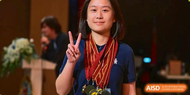 A female student smiles proudly while wearing multiple gold medals around her neck at International Studies Center Of Chongqing Nankai Secondary School.