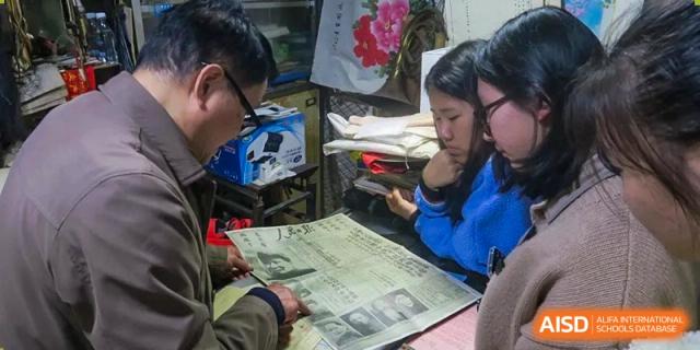 Two students look over a newspaper together while working in a classroom at International Studies Center Of Chongqing Nankai Secondary School.