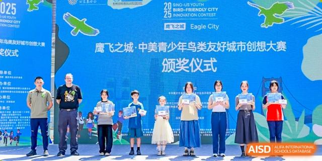 Four students stand on a stage in front of a blue banner during a formal awards ceremony at International Studies Center Of Chongqing Nankai Secondary School.
