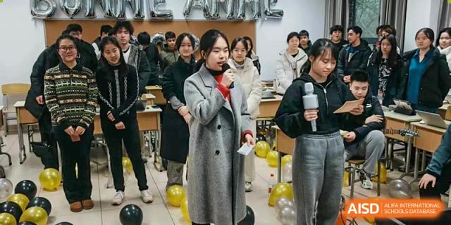 A student speaks into a microphone during a social event decorated with balloons at International Studies Center Of Chongqing Nankai Secondary School.