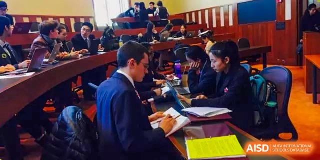 Students in formal attire participate in a simulated committee meeting or debate at International Studies Center Of Chongqing Nankai Secondary School.