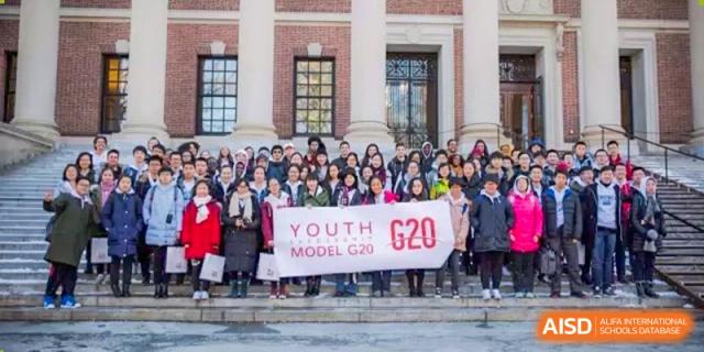 A group of students holds a "Youth Model G20" banner on the steps of a school building at International Studies Center Of Chongqing Nankai Secondary School.