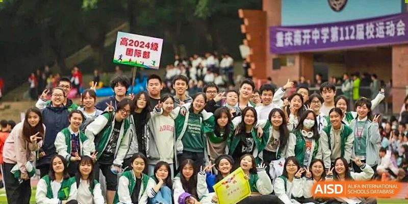 A large, enthusiastic group of students in green and white jackets gathers for a commemorative photo during a 2024 campus event at International Studies Center Of Chongqing Nankai Secondary School.