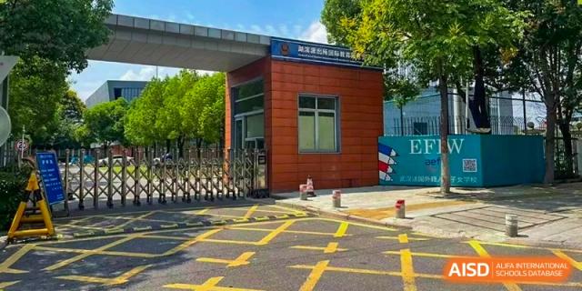 The main gated entrance of the campus featuring modern brick architecture and clear directional road markings at Ecole Française Internationale de Wuhan.
