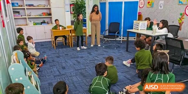A young student standing and speaking in front of classmates seated on a blue rug during a group lesson at Ecole Française Internationale de Wuhan.