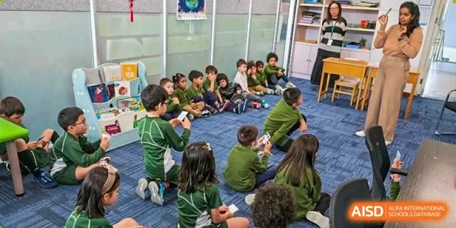 A group of young students in green uniforms sitting in a circle on the floor, engaging in a collaborative learning activity at Ecole Française Internationale de Wuhan.