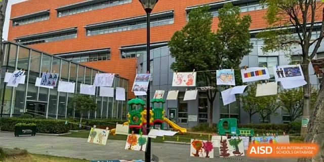 Student artwork displayed on lines across the playground with the modern school building behind at Ecole Française Internationale de Wuhan.