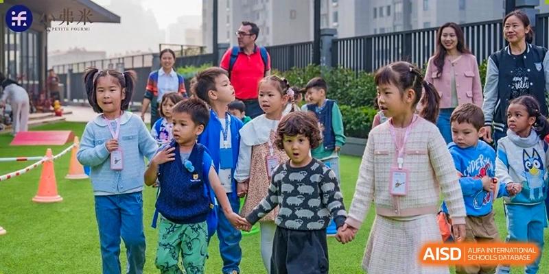 Young students holding hands walk together outdoors during a supervised school activity at Ecole Française Internationale de Wuhan.