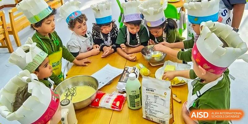 Students in chef hats gather around a table to learn about ingredients and food preparation at Ecole Française Internationale de Wuhan.