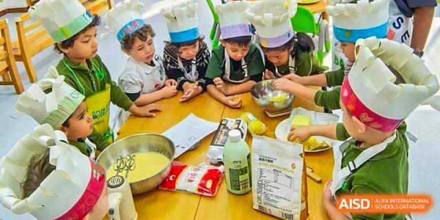 Students in chef hats gather around a table to learn about ingredients and food preparation at Ecole Française Internationale de Wuhan.