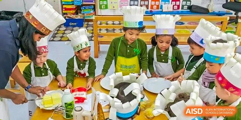 Young students in green aprons and chef hats proudly show off their culinary creations in a classroom at Ecole Française Internationale de Wuhan.