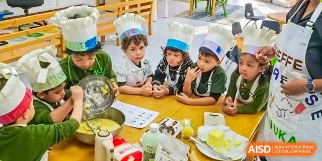 A group of students in chef hats gathered around a table for a cooking lesson and food preparation at Ecole Française Internationale de Wuhan.