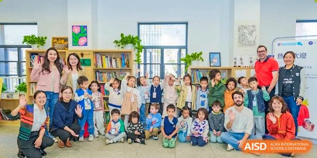 A large group of young students and their teachers pose for a group photo in a bright school library at Ecole Française Internationale de Wuhan.