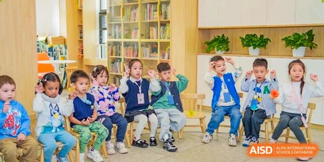 Students sitting in a circle on small wooden chairs, participating in a teacher-led lesson or story time at Ecole Française Internationale de Wuhan.
