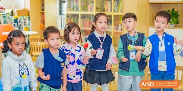 Young students standing together in a classroom, holding small colorful crafts during a group activity at Ecole Française Internationale de Wuhan.