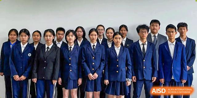 Group of students standing formally in dark blue blazers and ties against a plain white background at Shenzhen Senior High School International Division.