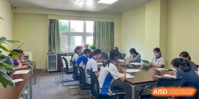 Students in athletic and formal uniforms sitting at a conference table for a meeting in a classroom at Shenzhen Senior High School International Division.